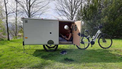 Fahrradanhänger Martha steht auf einer Wiese mit einem Pedelec.