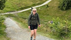 Eine Frau beim wandern mit Kühen im Hintergrund.