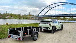 Faltos-Anhänger steht mit Kia EV3 vor einem Fluss. 