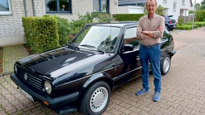 Mann steht neben altem VW Auto.