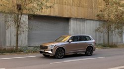 Volvo XC90 steht auf einer Straße vor modernem Gebäude.