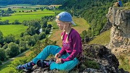 Ein Kind sitzt auf einem Stein und geniest die Aussicht.