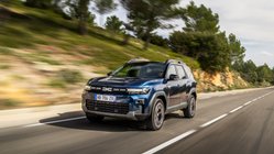 Dacia Bigster fährt bei Sonnenschein auf einer Landstraße.