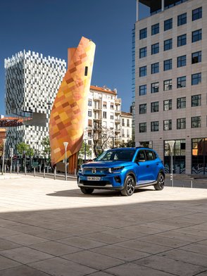 Citroen ë-C3 parkt vor moderner Stadtkulisse.