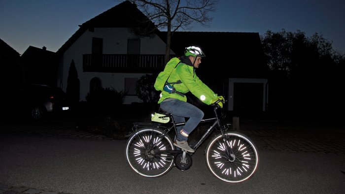 Ein Radfahrer mit reflektierender Kleidung in der Nacht.