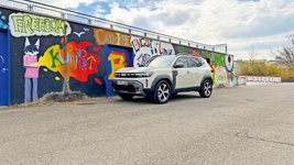 Dacia Duster Hybrid 140 parkt vor einer bunt bemalten Wand 