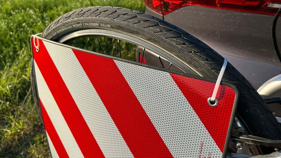 Befestigung einer Warntafel am Fahrradträger eines Autos. 