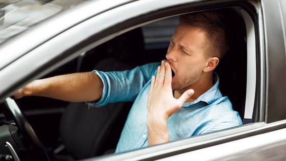 Autofahrer gähnt am Steuer seines Autos. 