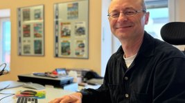ARCD-Grafiker Horst Holler sitzt am Schreibtisch. 