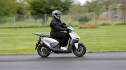 Eine Frau fährt den Elektroroller Honda CUV e