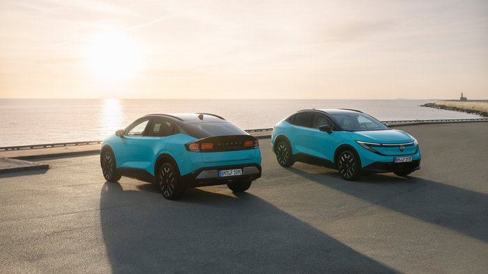 Zwei Nissan Leaf stehen auf einem Parkplatz am Meer.