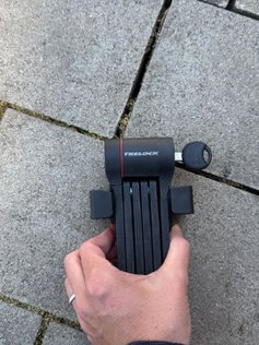 Eine Frau hält ein Faltschloss Trelock FS480 in der Hand.
