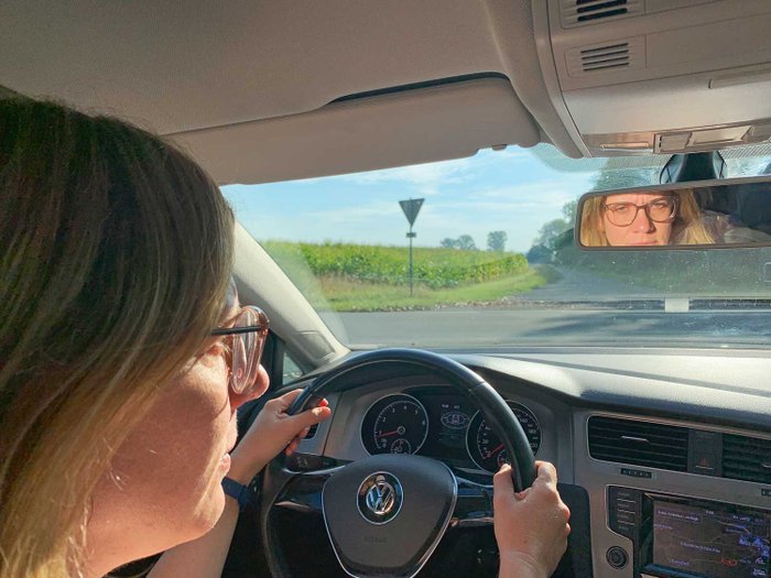 Eine junge Frau mit Brille sitzt am Steuer eines Pkw.