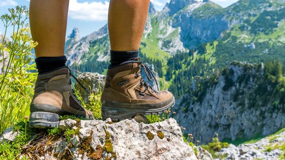 Beine eines Mannes mit Bergschuhen in alpinem Gelände