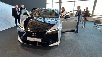 Auto steht in einem Raum, umgeben von Menschen. 