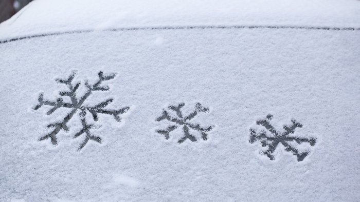 Schneebedeckte Autoscheibe mit Schneeflockensymbolen.