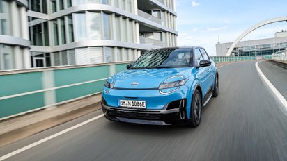 Nissan Micra EV fährt auf der Straße einer großen Stadt.