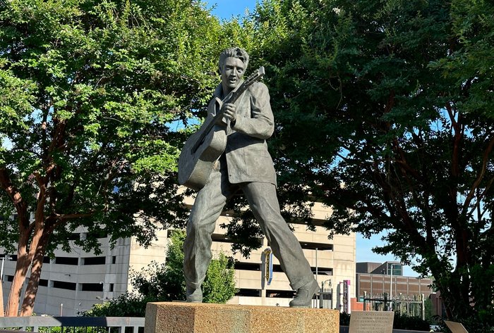 Eine Statue von Elvis Presley mit Gitarre im Park.