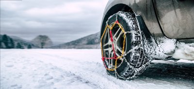 Autoreifen in Schneeketten auf verschneiter Straße.