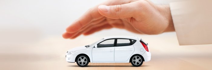 Hand schwebt schützend über Modellauto.