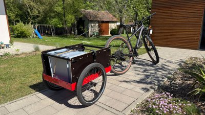In einem Fahrradanhänger steht eine Box.