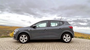 Grauer Dacia Sandero von der Seite auf einem Parkplatz.