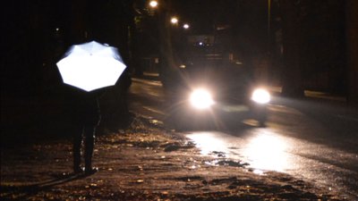 Regenschirm im Scheinwerferlicht eines Autos.