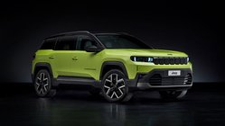 Grüner Jeep Compass vor dunklem Hintergrund.