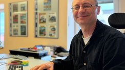 ARCD-Grafiker Horst Holler sitzt am Schreibtisch. 