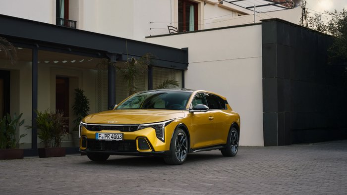 Gelber Kia K4 steht vor einem Gebäude.