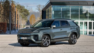 KGM Actyon Hybrid parkt vor einem modernen Gebäude aus Glas.