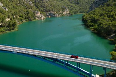 Roter Mazda MX-5 fährt über Brücke über Krka-Fluss.