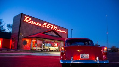 Blick auf ein Route-66-Museum mit Neonschriftzug und Classic Cars im und vor dem Museum.