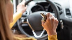 Ältere Frau raucht E-Zigarette beim Autofahren.