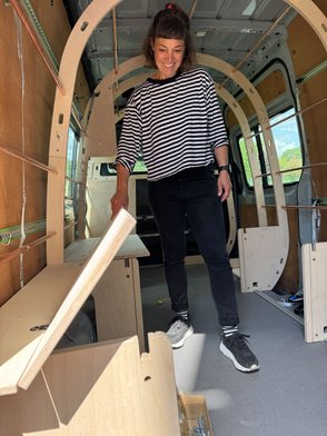 Eine Frau zeigt die Gepäckfächer. 