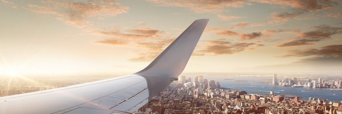 Flugzeug fliegt über Stadt und Gewässer. 