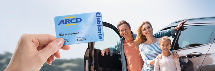 Eine Hand mit einer ARCD-Clubkarte, im Hintergrund eine Familie die vor einem Auto steht.
