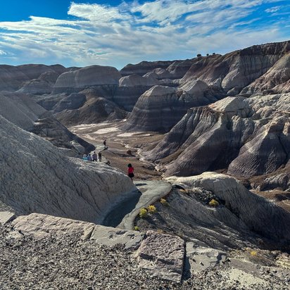 Besucher laufen durch die steinerne Hügellandschaft des Nationalparks Petrified Forest.