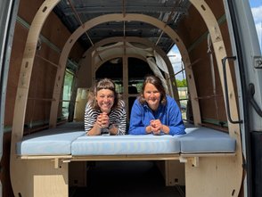  Zwei Frauen liegen auf dem Bett des Moby Camper. 
