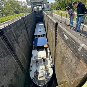Zwei Personen schauen auf ein großes Boot, das in einer Schleuse liegt.