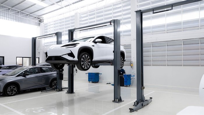  Ein E-Auto steht reparaturbereit auf einer Hebebühne in einer Werkstatt.