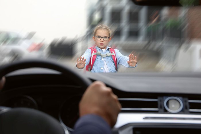 Ein Mädchen taucht plötzlich vor einem Auto auf.