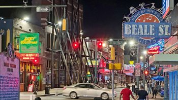 Belebte Straße mit Leuchtreklamen von Musikclubs und Restaurants.