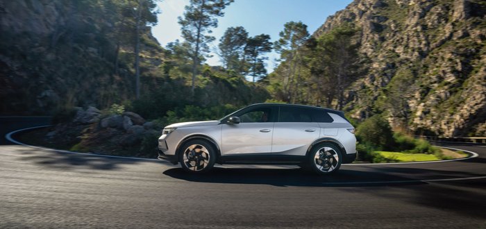 Seitliche Ansicht des Opel Grandland PHEV während er auf einer Landstraße fährt.