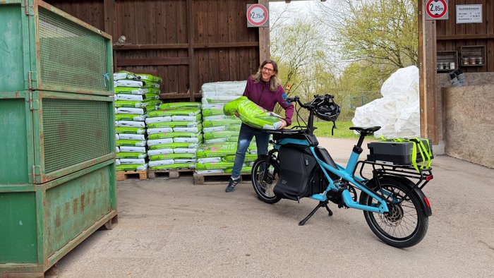 Das Lastenrad Cago CS 150 wird mit einem Sack Erde am Wertstoffhof beladen. 
