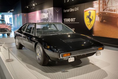 Schwarzer Ferrari Dino 308 GT4 in Ausstellung vor einem Foto mit Elvis.