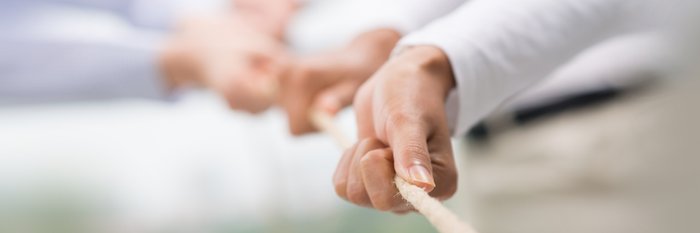 Hände ziehen an einem Strang.