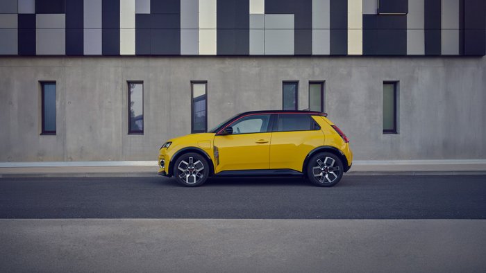Renault 5 E-Tech parkt vor einem modernen Gebäude.