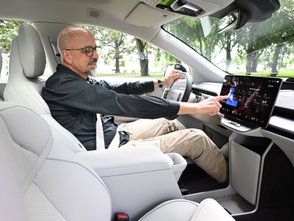 Ein Mann zeigt auf den Bildschirm des Volvo EX60. 