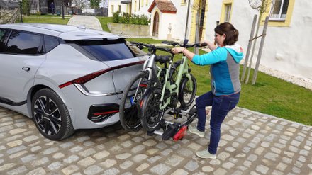Frau tritt auf einen Fußhebel eines Fahrradträgers.  